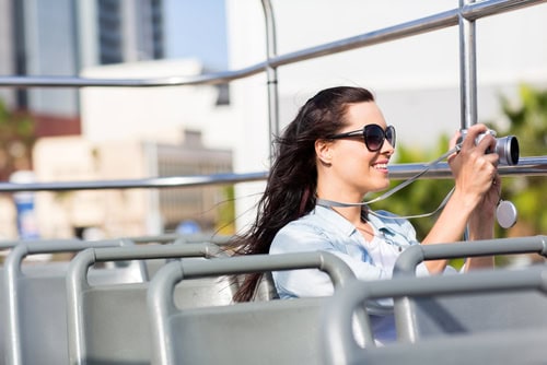 Frau fotografiert vom offenen Verdeck eines Hop-on/Hop-off-Busses