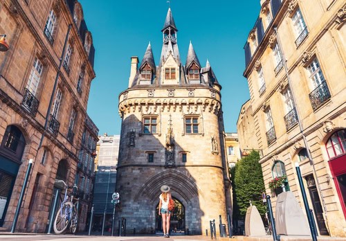 Femme debout devant la Porte Cailhau à Bordeaux, France